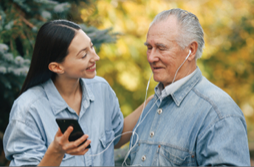 Young adult showing senior how to use phone