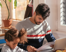Father working on computer with daughter next to him